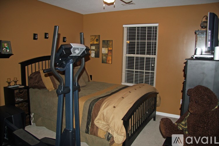 A room with a bed, a television, and a teddy bear.