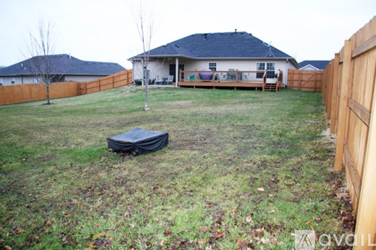 A backyard with a fence and a house in the background.