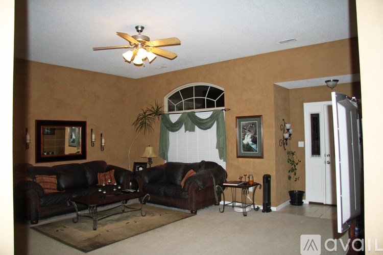 A living room with a black couch and a ceiling fan.
