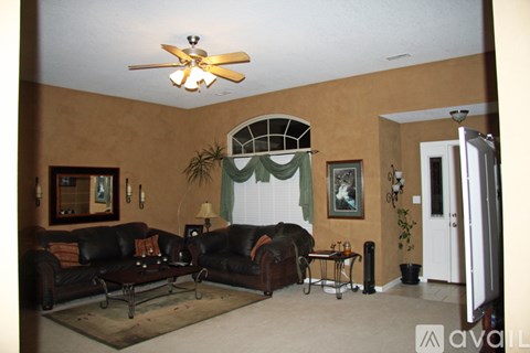 A living room with a black couch and a ceiling fan.