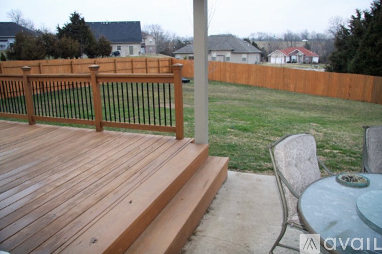 A wooden deck with a table and chairs is in front of a fence.