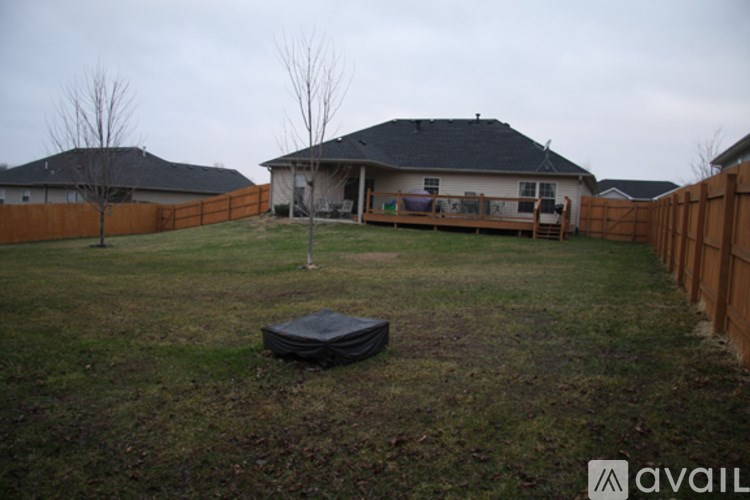 A backyard with a fence and a house in the background.