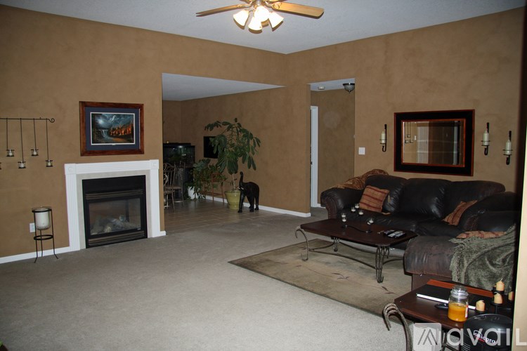 A living room with a fireplace and a ceiling fan.