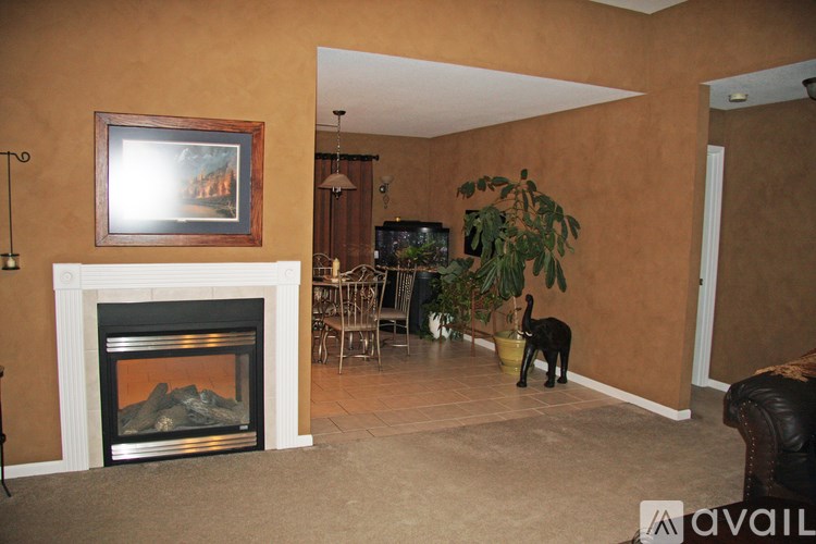 A dog is standing in a living room with a fireplace and a painting on the wall.