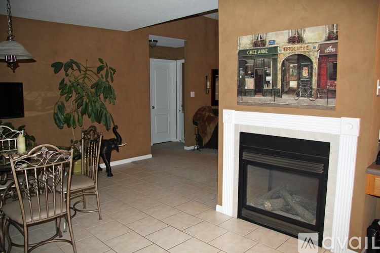A living room with a fireplace and a painting of a street scene on the wall.