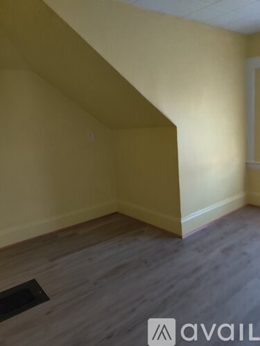 A room with a wooden floor and a wall with a window.
