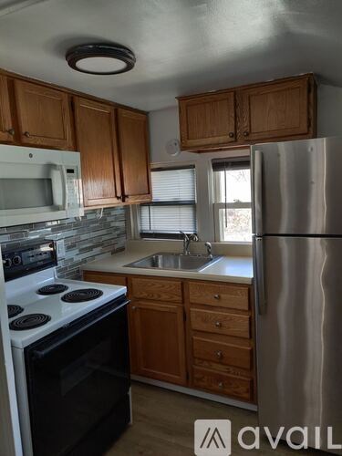 A kitchen with wooden cabinets and a stainless steel refrigerator.
