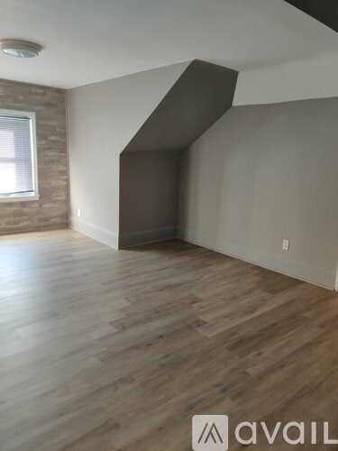 A room with wooden flooring and a window.
