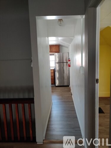 A hallway with a refrigerator in the background.