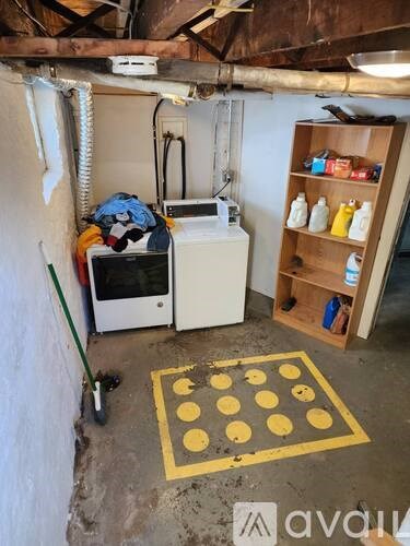 A room with a white fridge, a yellow floor mat and a wooden shelf.