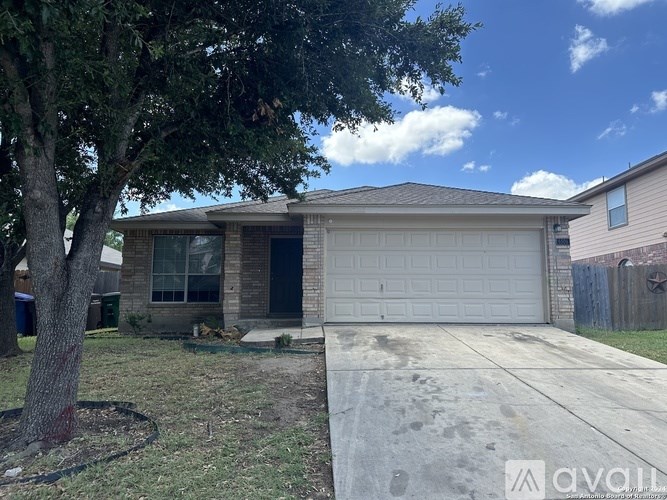 A house with a garage and a tree in front.