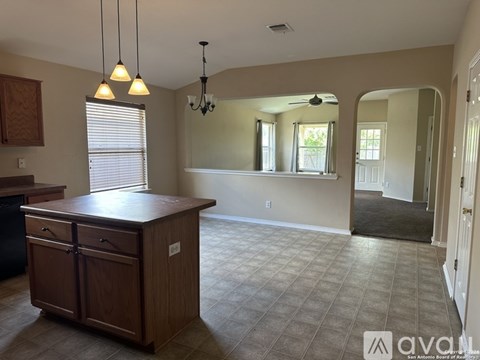 A kitchen with a wooden island and a chandelier.