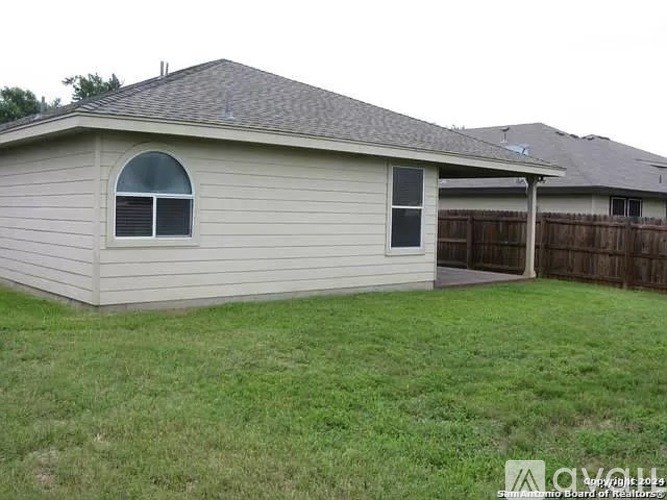 A house with a grey roof and a fence in the backyard.