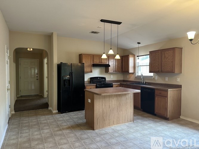 A kitchen with a black fridge and wooden cabinets.