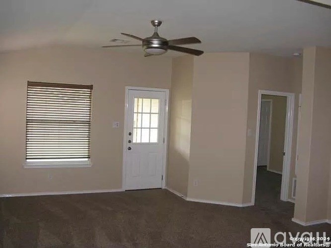 A room with a ceiling fan and a window with blinds.