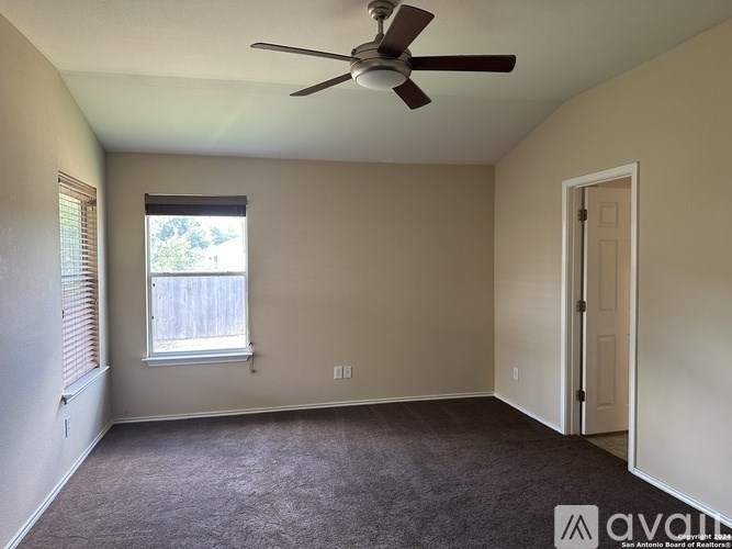 A room with a ceiling fan and a window with blinds.