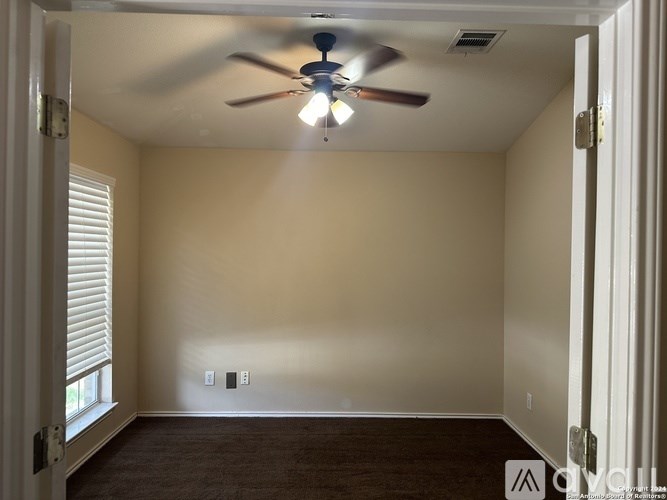 A room with a ceiling fan and a window with blinds.