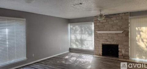 A living room with a fireplace and a window with blinds.