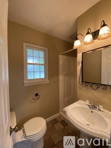 A bathroom with a toilet, sink, and window.