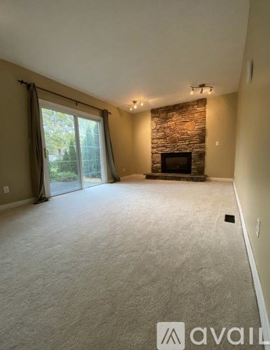 A living room with a stone fireplace and sliding glass doors.