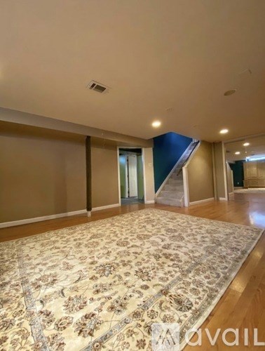 A room with a patterned carpet and wooden flooring.
