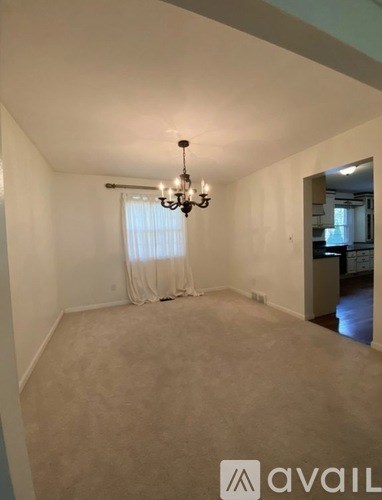 A room with a chandelier and a window with curtains.