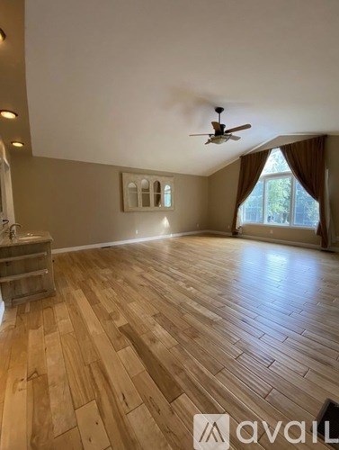 A room with wooden flooring and a ceiling fan.