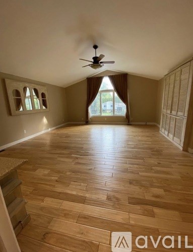 A room with wooden flooring and a ceiling fan.