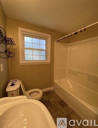 A bathroom with a toilet, tub, and window.