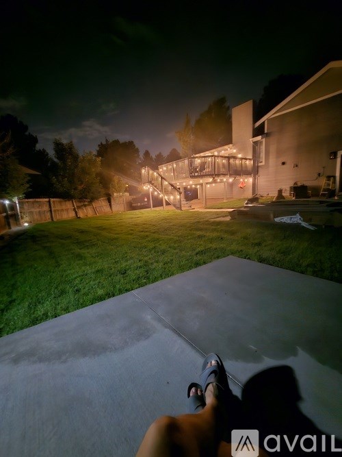 A person is sitting on a concrete surface with their feet on a skateboard.
