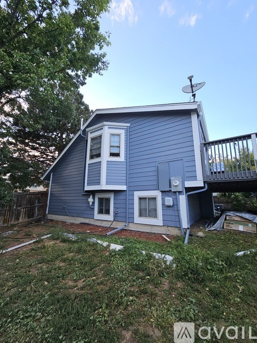 A blue house with a white door and a satellite dish on the roof.