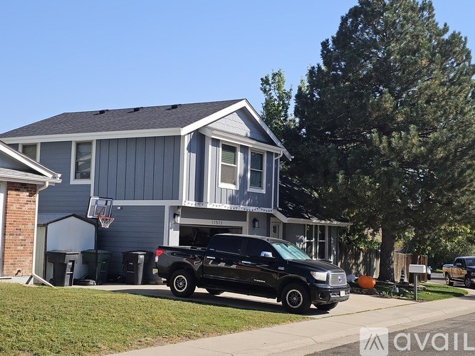 A black truck is parked in front of a two-story house.