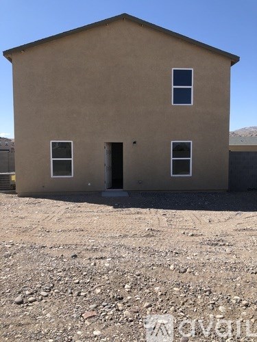 A small brown house with a gravel ground in front.