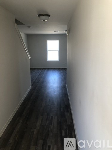 A long hallway with wood floors and a window.