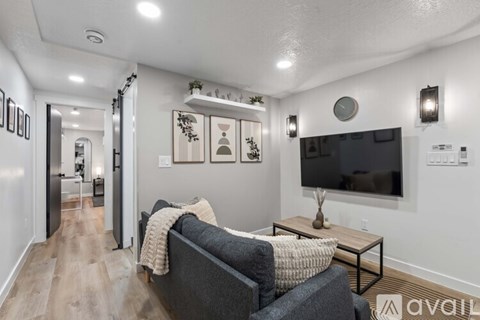 A living room with a grey couch and a flat screen TV mounted on the wall.