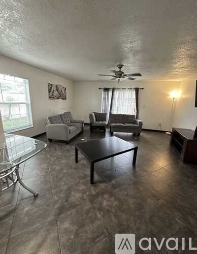 A living room with a glass table and a fan on the ceiling.