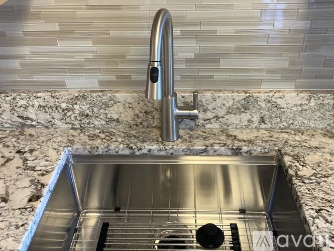 A modern kitchen sink with a chrome faucet and a marble countertop.
