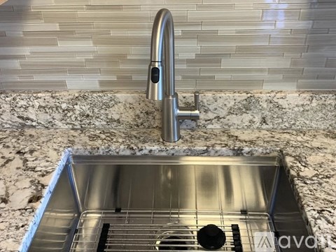 A modern kitchen sink with a chrome faucet and a marble countertop.