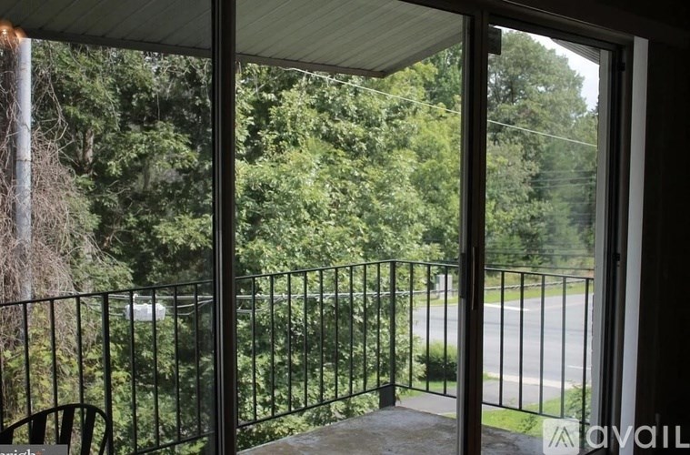 A balcony with a black railing overlooks a green road.