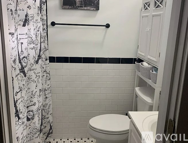 A white toilet in a bathroom with a black and white shower curtain.
