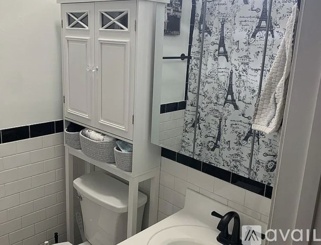 A bathroom with a toilet, a sink, and a shower curtain with Eiffel Tower prints.