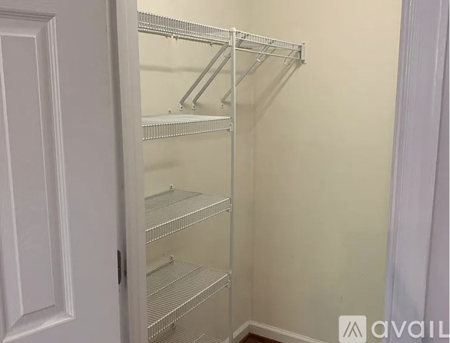 A white door is open to a white wall with a metal shelving unit.