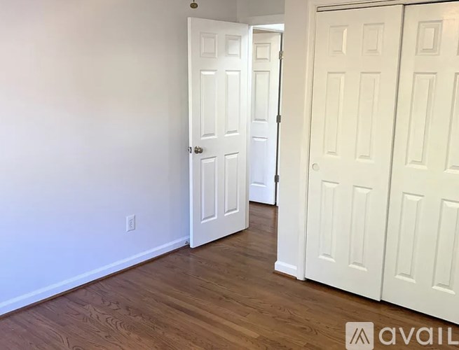 A room with two white doors and wooden flooring.