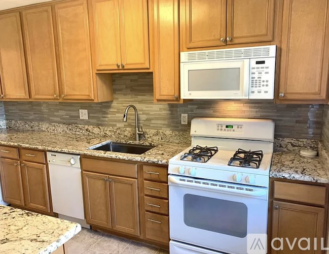 A kitchen with wooden cabinets and a white stove top oven.