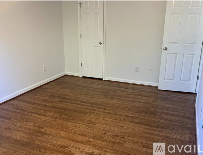 A room with wood flooring and two white doors.
