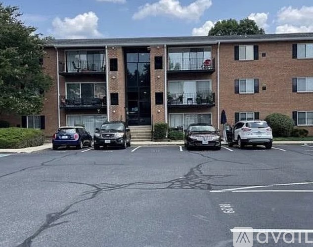 A parking lot in front of a brick apartment building with cars parked.