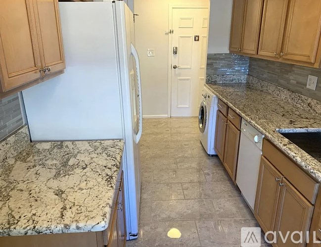 A kitchen with a marble countertop and wooden cabinets.