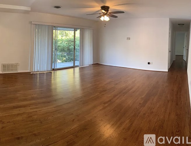 A spacious room with wooden flooring and a ceiling fan.