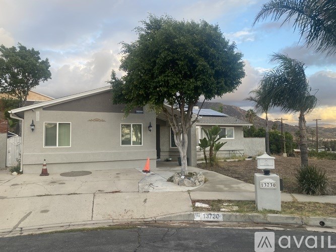 A house with a grey roof and a tree in front of it.