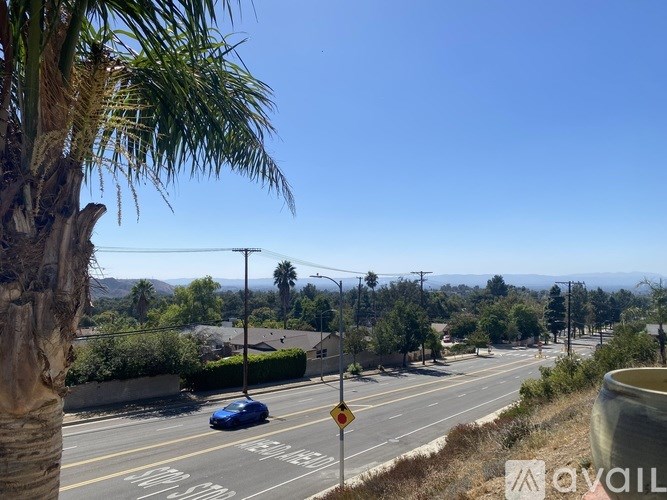 A blue car is driving on a road with a yellow sign.